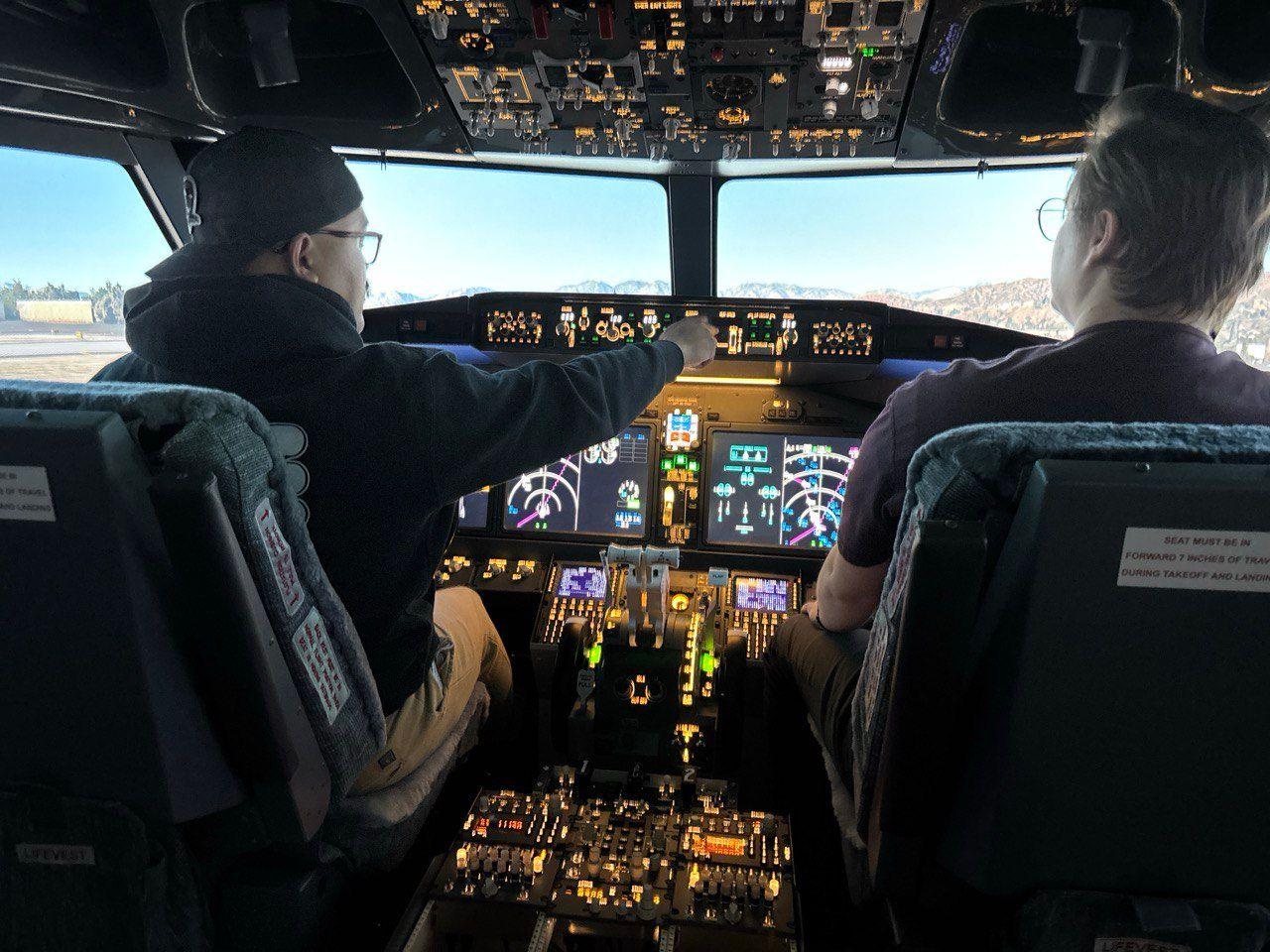 Two people sitting in a Boeing 737 MAX flight simulator cockpit during a realistic flight experience