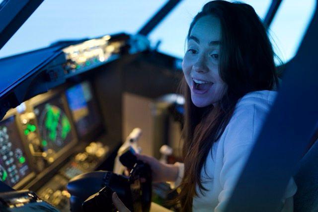 Woman smiling while flying a commercial aircraft simulator at WeFly